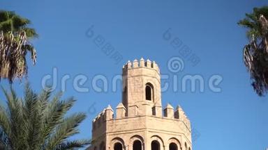 一座古老的塔立在棕榈树旁边。 阿拉伯国家。 旧的黄砖。 基本观点
